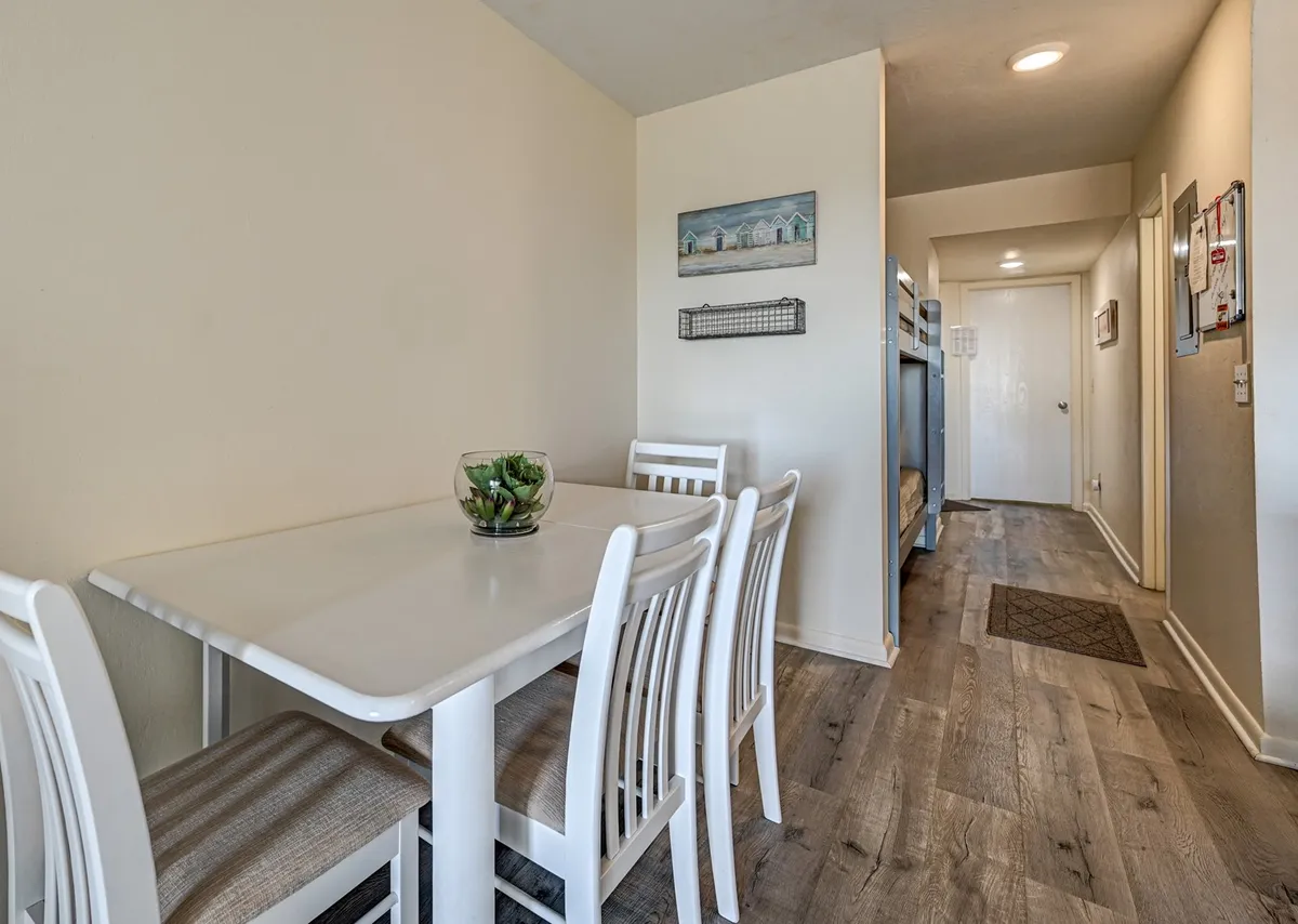 A dining area with a modern table set for a meal, adorned with a succulent centerpiece. The scene is open and inviting, with a hallway leading to other rooms—suggesting a seamless flow between the kitchen and dining space, perfect for gatherings and memorable family dinners.