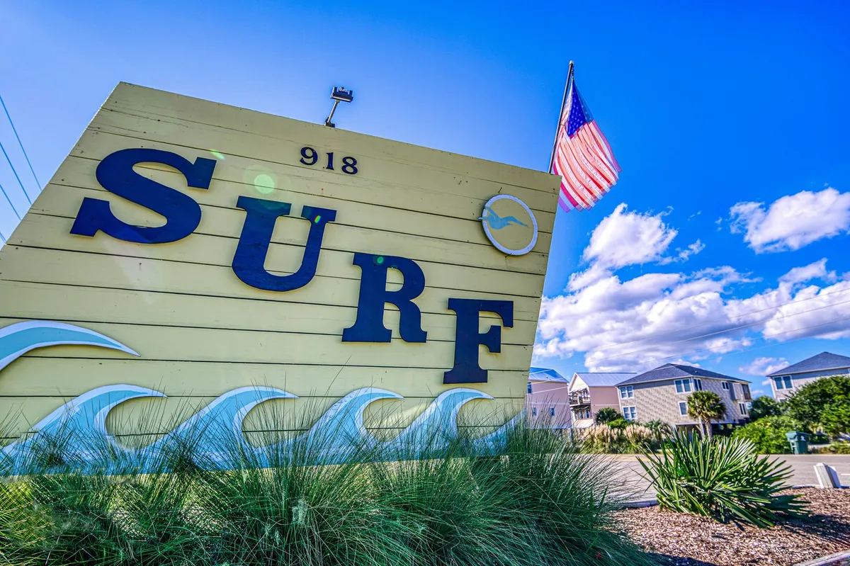 An energetic exterior scene featuring a bold 'SURF' sign, an American flag, and waves motif—hinting at local culture, community spirit, and nearby beach activities. The vibe is friendly and welcoming, emblematic of Surf City's lively atmosphere.