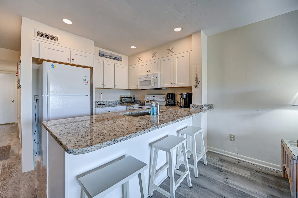 The image features a kitchen with gleaming granite countertops, crisp white cabinetry, and stainless steel appliances. The countertop provides ample space for meal preparation, while the modern appliances and inviting mood make it perfect for cooking or entertaining guests. The scene radiates a welcoming, relaxed vibe that aligns with cozy breakfast moments and celebratory meals.